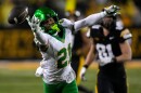An Oregon football player reaches for a football that is just out of his reach