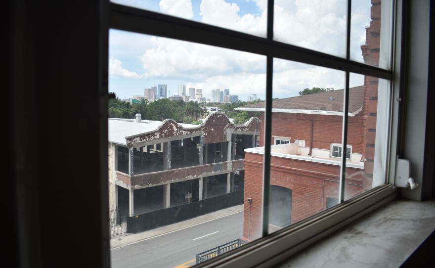 A view of a dilapidated building is visible through the third-story window of another building. 