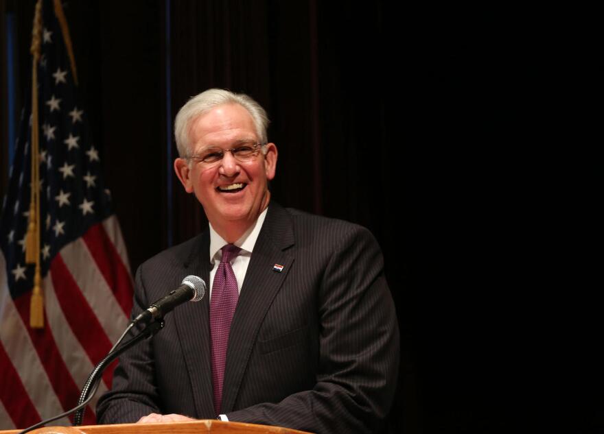 Jay Nixon speaks behind a podium, an American flag is seen in the background.