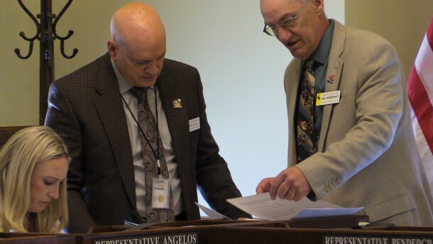 3 people look at papers by an american flag