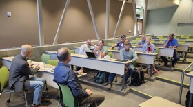 State leaders Tim Davis and Tim Hawkes sit at the front of the auditorium facing seven Box Elder community members sitting at desks. Autoliv Auditorium at USU Brigham City campus. June 25, 2024.