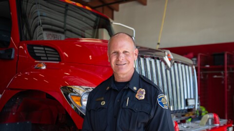 Monterey fire chief Patrick Moore stands in front of a fire engine inside a fire station garage.