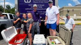 People pose in front of a cooler of meat