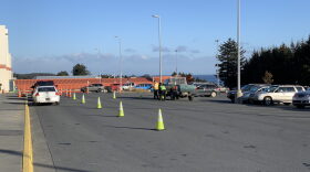Cones marking testing lanes are packed away, as cars line up for COVID testing.