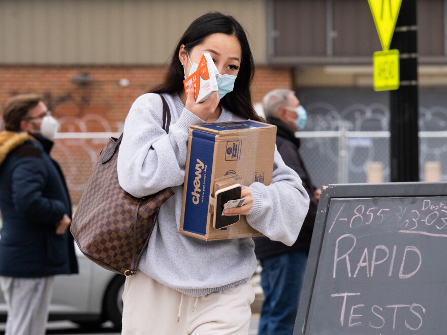 A woman picks up COVID-19 rapid antigen test kits at the Watha T. Daniel-Shaw Neighborhood Library in Washington, D.C., in late December.