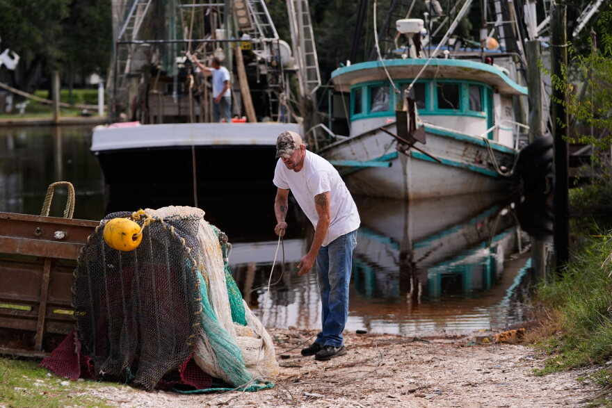 Boat owner Tony Rice, foreground, and his friend Lance Connor haul doors onto his boat to secure it as Hurricane Isaias approaches Bayou La Batre, Ala., Thursday, Oct. 8, 2026. (AP Photo/Gerald Herbert)