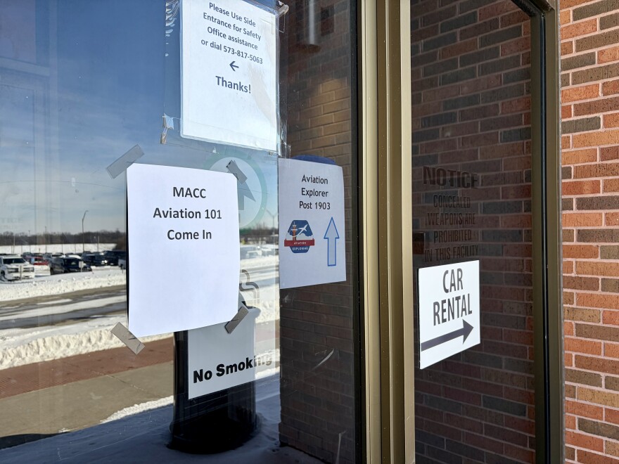 Signs on the glass doors of the former terminal at the Columbia Regional Airport. One of them reads "MACC Aviation 101 Come In"