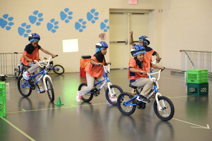 Second-graders ride in circles around the school's indoor gym.