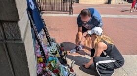 Mary Ellen Price helps Bob Tomaszewski light a candle outside the Blue Jackets' arena in Columbus to honor player Johnny Gaudreau. 