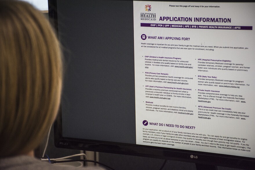 A photo of a woman filling out a medicaid form on a computer. 