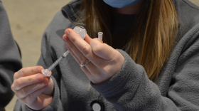 A health care worker fills a vial with the Pfizer vaccine at a COVID shot clinic at the Ohio State Fairgrounds in January 2021.