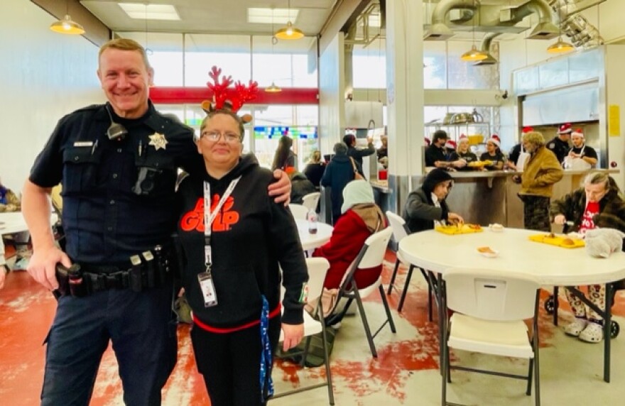 Eugene Police officer Dave Clark has been on patrol in west Eugene for 12 years and organizes the Holiday Dinner at the Lindholm Center. He poses here with Teresa Patterson who manages the front desk at the day center and helps every event there run without a hitch.