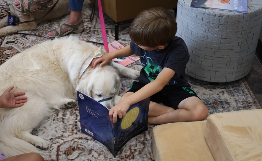 Boy reading to a dog at the Read to a Dog station at CALF. Photo by Allison Diaz.