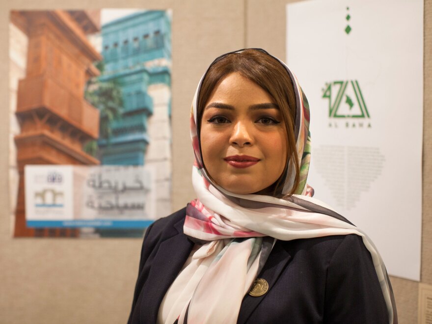 Rana Fatami stands in front of a poster for her Historical Jeddah app.