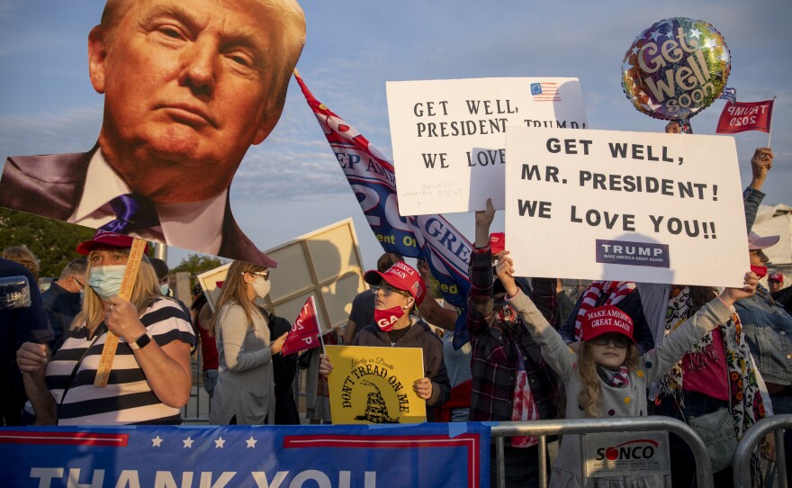 On left, Darla Cable of Cabin John, Md., holds a Trump cutout as others show their signs.