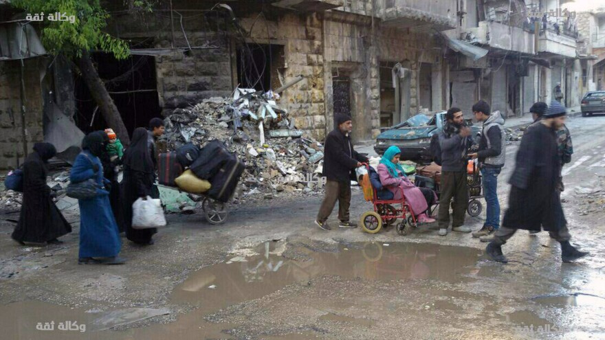 Civilians gather for evacuation from eastern Aleppo, Syria, on Thursday, in a photo released by a pro-opposition media group. Syrian activists said residents in eastern Aleppo are starting to board buses and ambulances, the first step in an evacuation that is part of the rebel enclave's effective surrender.