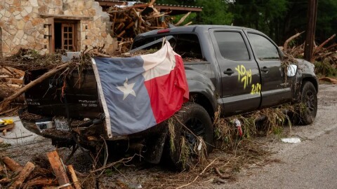 A pickup truck on the side of the road on Highway 39 in Hunt has a Texas flag hanging on its side with the date of the flood spray-painted on the side.