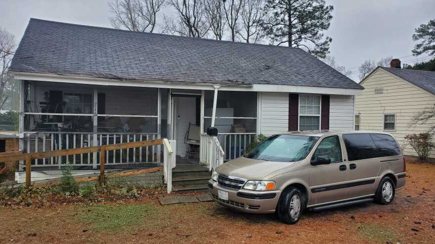 Evelyn Davis' house with white siding in Wallace, Duplin County. An accessibility ramp leads to the front door. A beige van is parked in front.