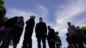 Migrants stand in a line. 