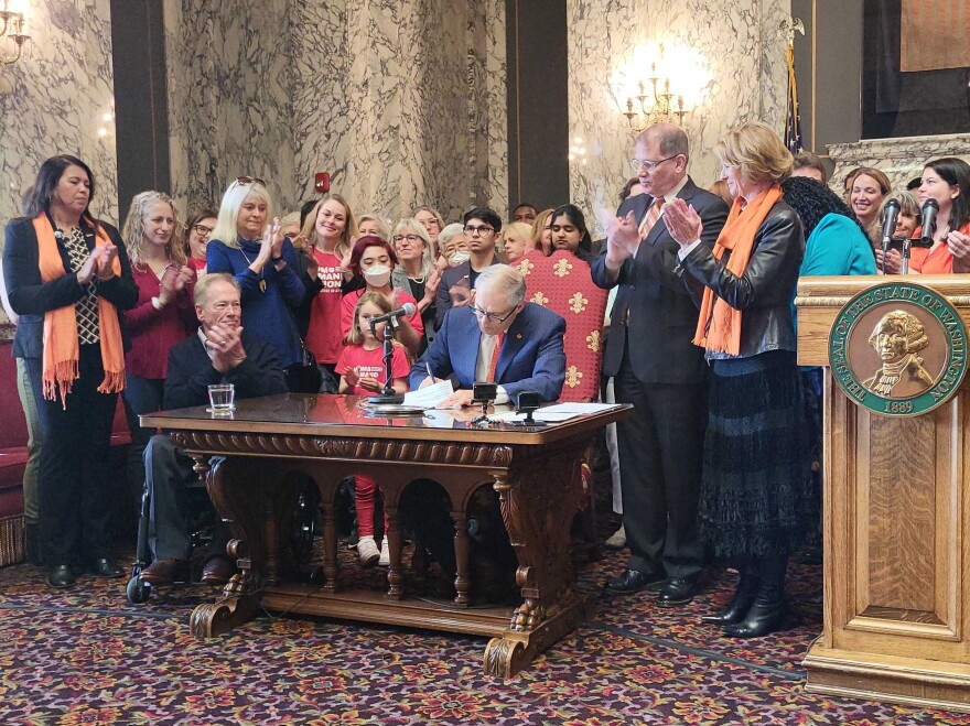 Washington Governor Jay Inslee signs a new gun bill into law surrounded by gun reform advocates and lawmakers. 