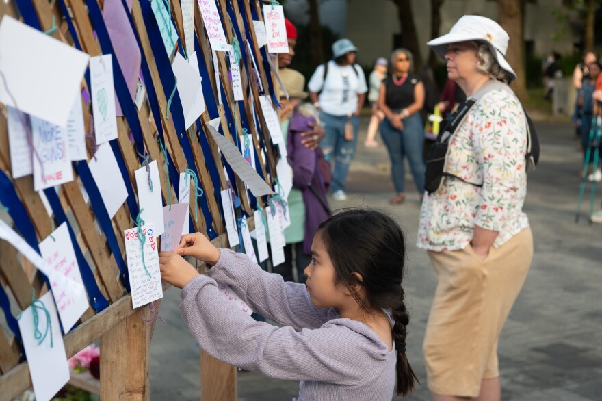 A young girl leaves a message at a silent vigil for the Seattle Center shooting victims.