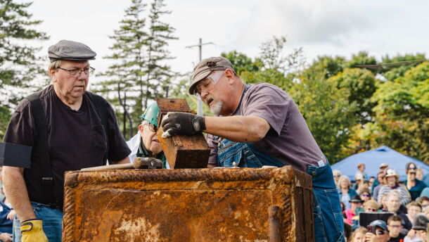 Three men look inside of the a rusted metal box that was removed from a thousand-pound, century-old, safe. 