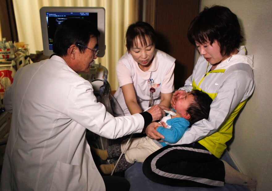 A doctor examines the thyroid of a child at a temporary housing complex in Nihonmatsu, about 31 miles from the tsunami-crippled Fukushima Dai-ichi nuclear power plant, in 2013.