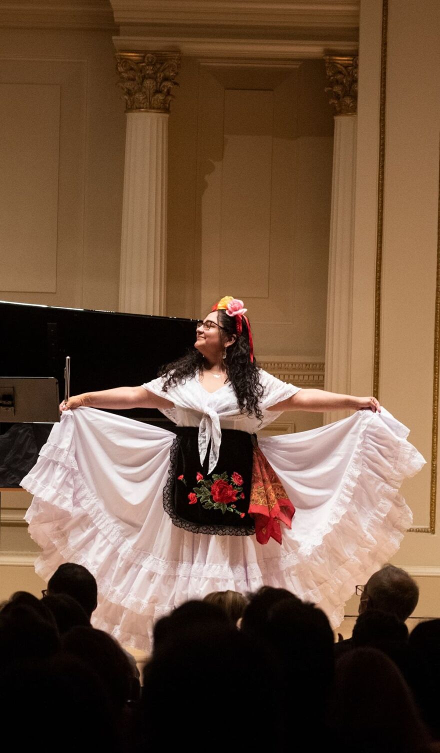 A woman in a white dress with a floral head embellishment.