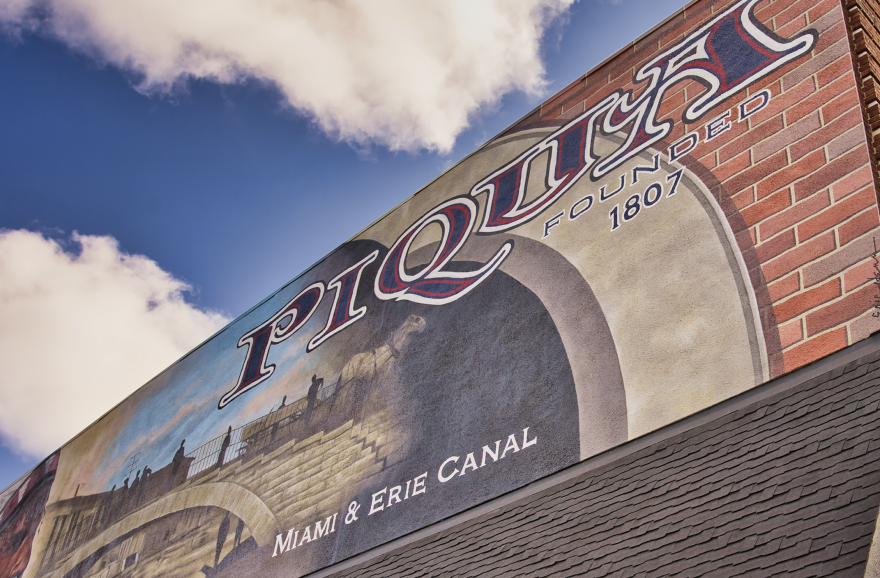 The piqua city sign on a brick wall