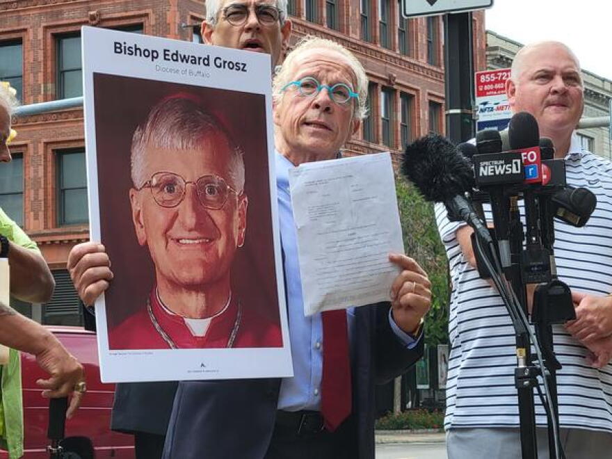 Attorney Jeff Anderson holds up a photo of retired Buffalo Auxiliary Bishop Edward Grosz and a copy of a Child Victims Lawsuit.
