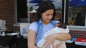 A mother holds her baby during the Womb to World community maternal health event on Saturday, Feb. 21, 2026, in Gainesville, Fla. The event brought families together for health resources, workshops and support. (Annaleis Holz/WUFT)