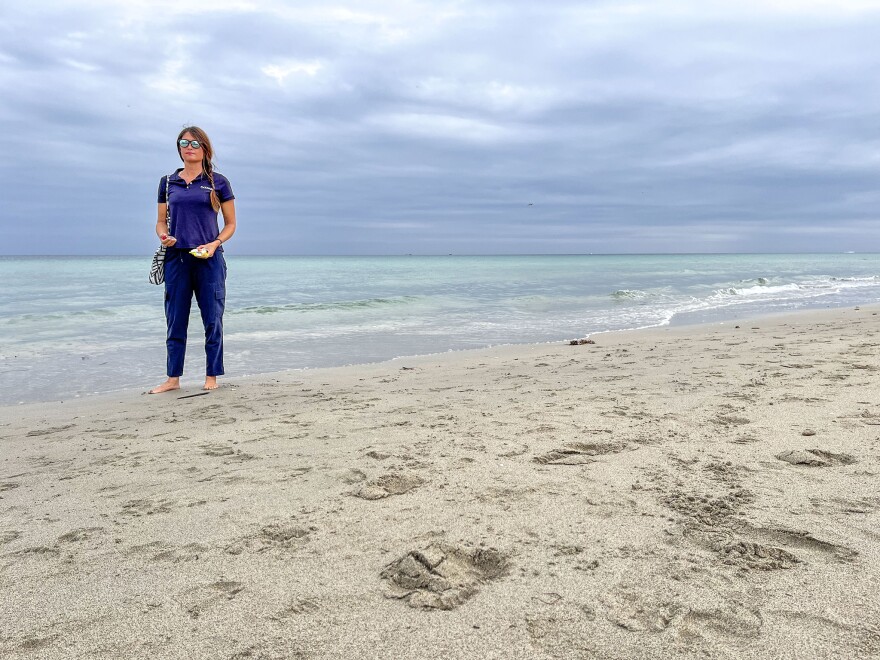 Catherine Uden stands on the shoreline where she frequently visits, holding plastic she picked up from the sand.