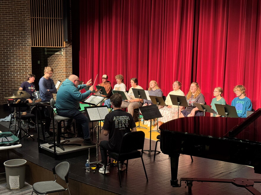 People sitting on a stage with a giant red curtain behind them