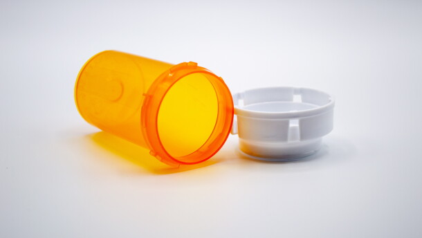 Empty orange medicine bottle with white cap isolated on white background.