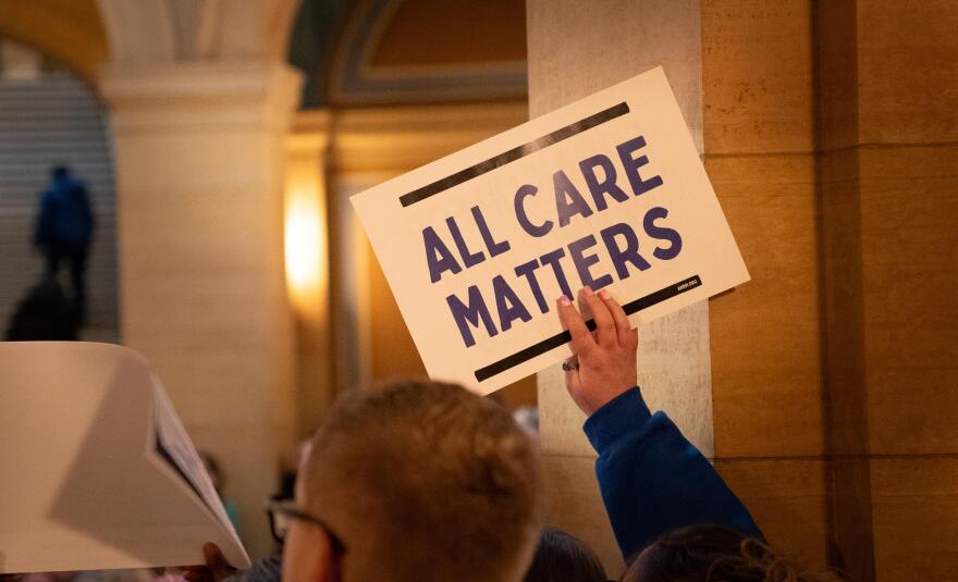 An advocate holds a sign during a Disability Day event at the Minnesota State Capitol in St. Paul on Tuesday, March 24, 2026. Participants raised concerns about proposed state budget cuts to disability services.