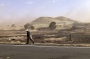 FILE - A U.S Army fire official walks along a section of burned grassland near Waimea, Hawaii, on Wednesday, Aug. 4, 2021. Hawaii increasingly seems under siege from disasters, and what is increasing most is wildfire, according to an analysis of Federal Emergency Management Agency records by The Associated Press. There were as many federally-declared disaster wildfires this month in Hawaii, as in the 50 years between 1953 and 2003. (AP Photo/Caleb Jones, File)