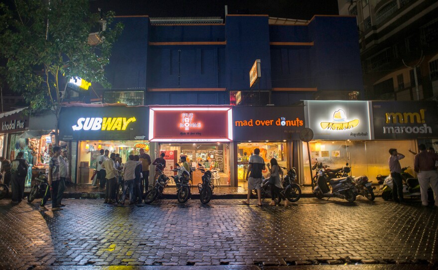 Pedestrians visit fast-food restaurants in Mumbai, India. Rapid urbanization in many developing countries is driving the demand for fast foods and highly processed, packaged foods.