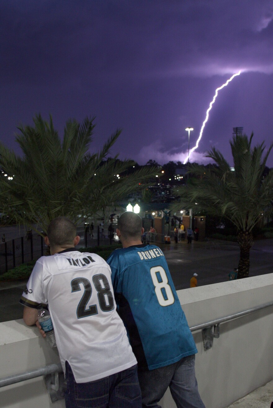 Jeffrey Moody, left, and his twin brother Joseph Moody wait out a lightning and rain storm at EverBank Field in Jacksonville. Floridians have a relatively higher chance of being impacted by lightning than other Americans. (AP Photo/Reinhold Matay)
