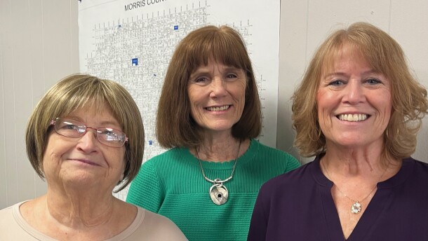 Three women standing and smiling.