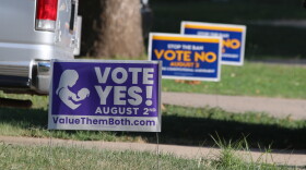 Political signs for the state constitutional amendment vote on abortion rights in Kansas sit near each other in yards in Overland Park.