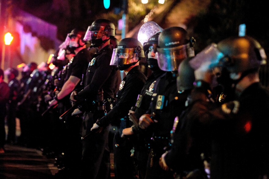 Police form a line as activists and supporters of residents of a homeless encampment protest at Echo Park Lake in Los Angeles late on March 24, 2021.