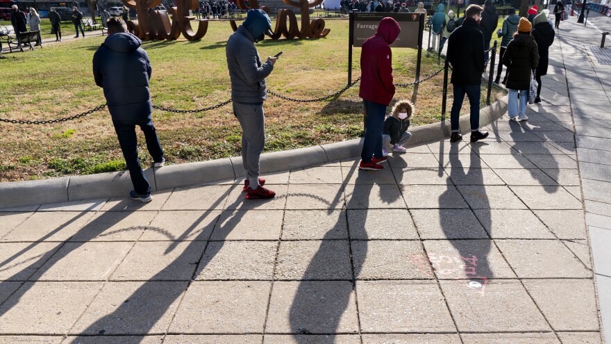 A line of people wait for COVID-19 testing at a D.C. Health- organized walk-up testing site at Farragut Square on Dec. 23, just blocks from the White House in Washington.