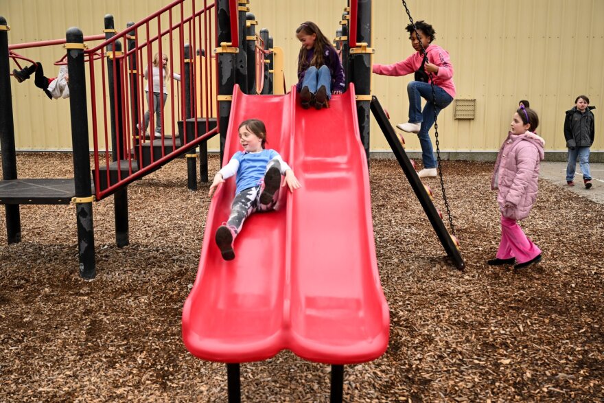 St. John Elementary student Melody Nelson, left, takes a turn on the slide with friends Cora Dennis, Mia Moseby and Charlotte Ward on Friday in St. John, Wash. The St. John School District is seeking voters to approve replacement levies, and their capital levy would help improve the minimalist playground.