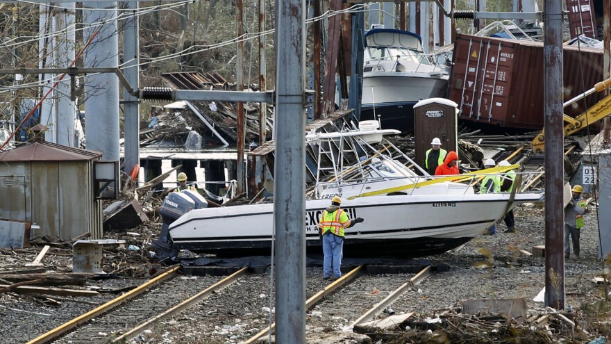 Workers try to clear boats and debris from the New Jersey Transit's Morgan draw bridge on Wednesday in South Amboy, N.J., after Monday's storm surge from Sandy pushed boats and cargo containers onto the train tracks.