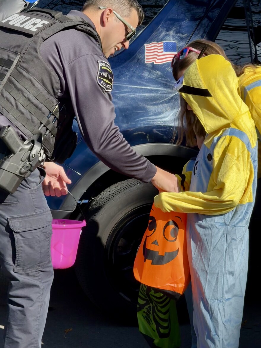 An Ann Arbor police officer gives candy to a young trick-or-treater at the 2024 Ann Arbor Halloween Parade.