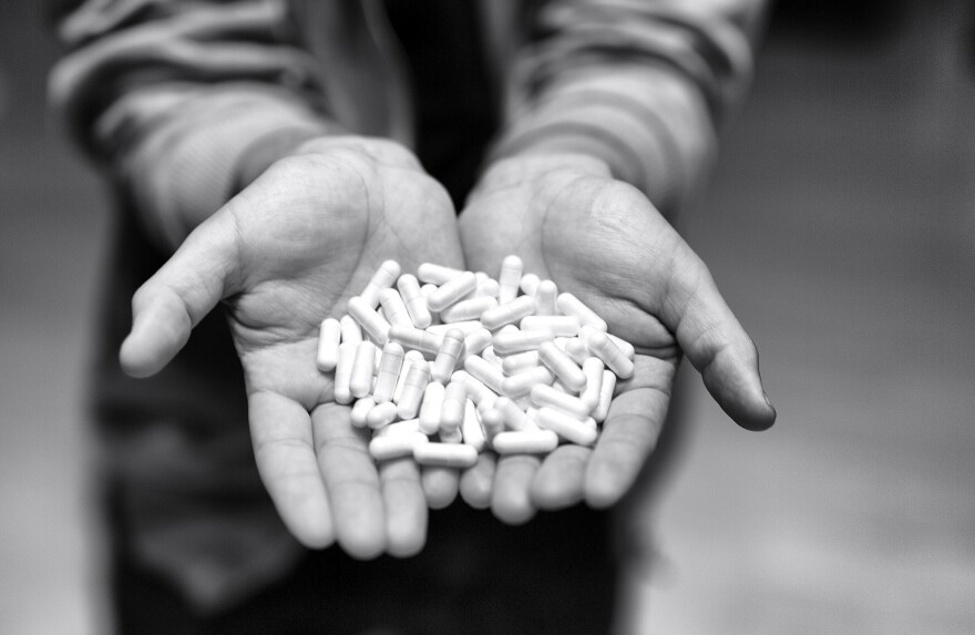 hands holding a pile of pills