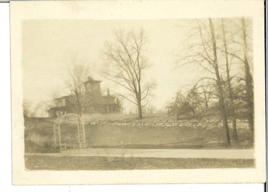 A sepia-toned photograph of a mansion from a distances.