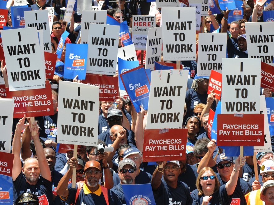 Protesters hold 'I want to work' signs at a rally in Los Angeles. According to Galston, unemployment will be sluggish as long as household debt remains high.