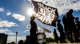 A woman holds a Black Lives Matter flag during an event in remembrance of George Floyd. (Kerem Yucel/Getty Images)