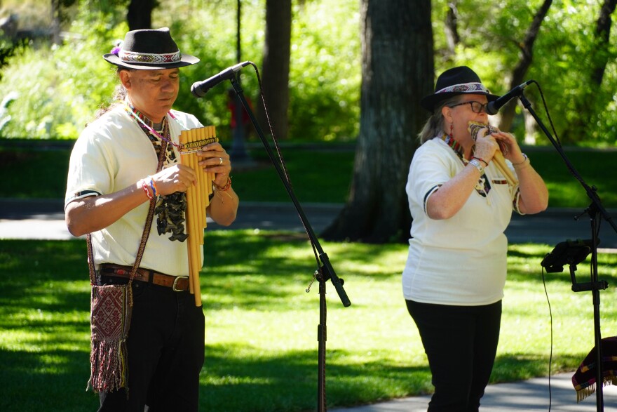 A couple dressed in Peruvian traditional clothing play Andean instruments.